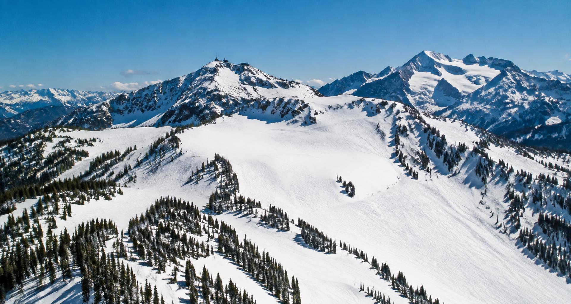 Vast alpine ski bowls and groomed runs on Whistler Blackcomb under a bluebird sky